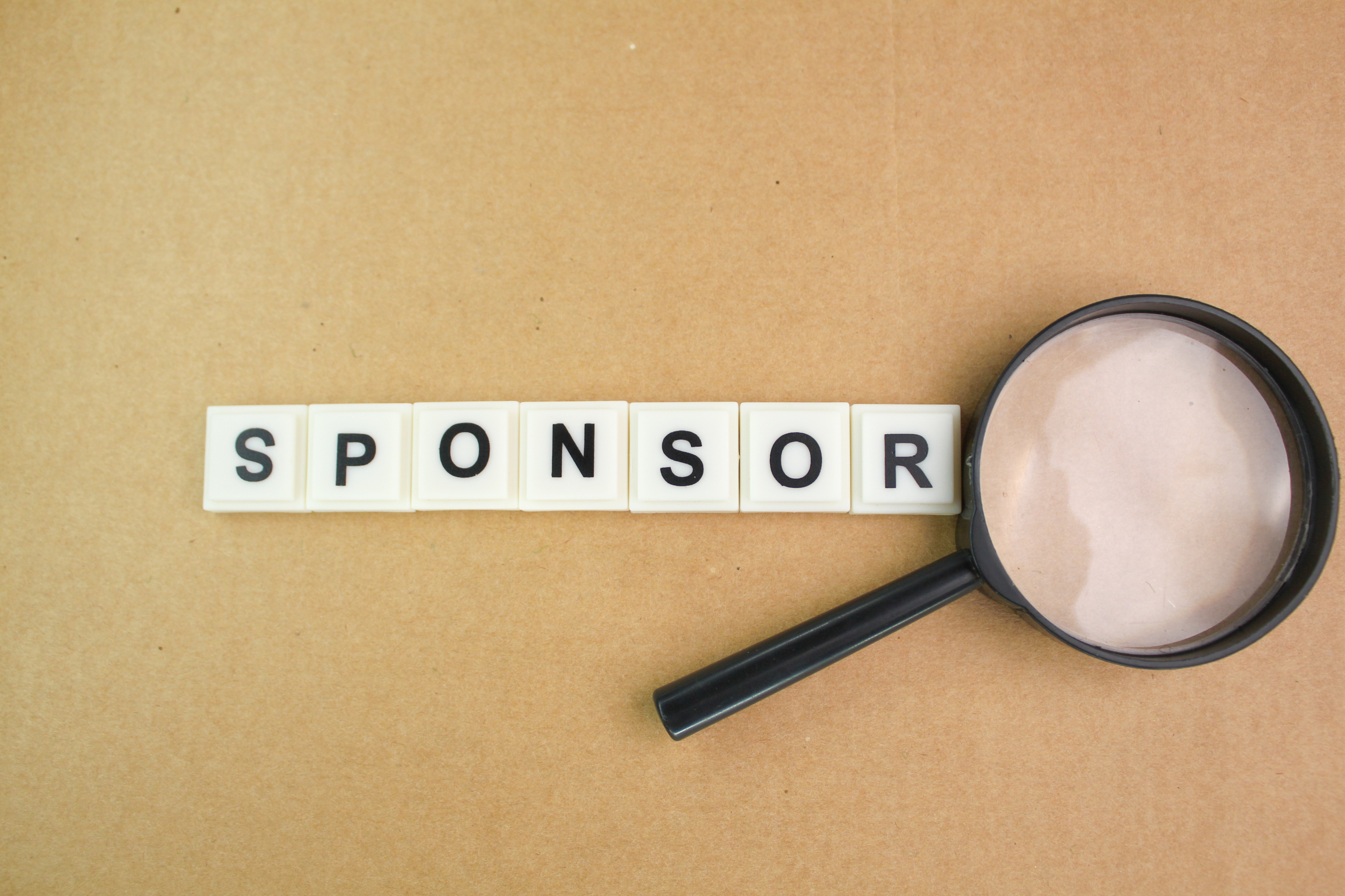 Woord sponsor met vergrootglas erbij om zoeken aan te duiden